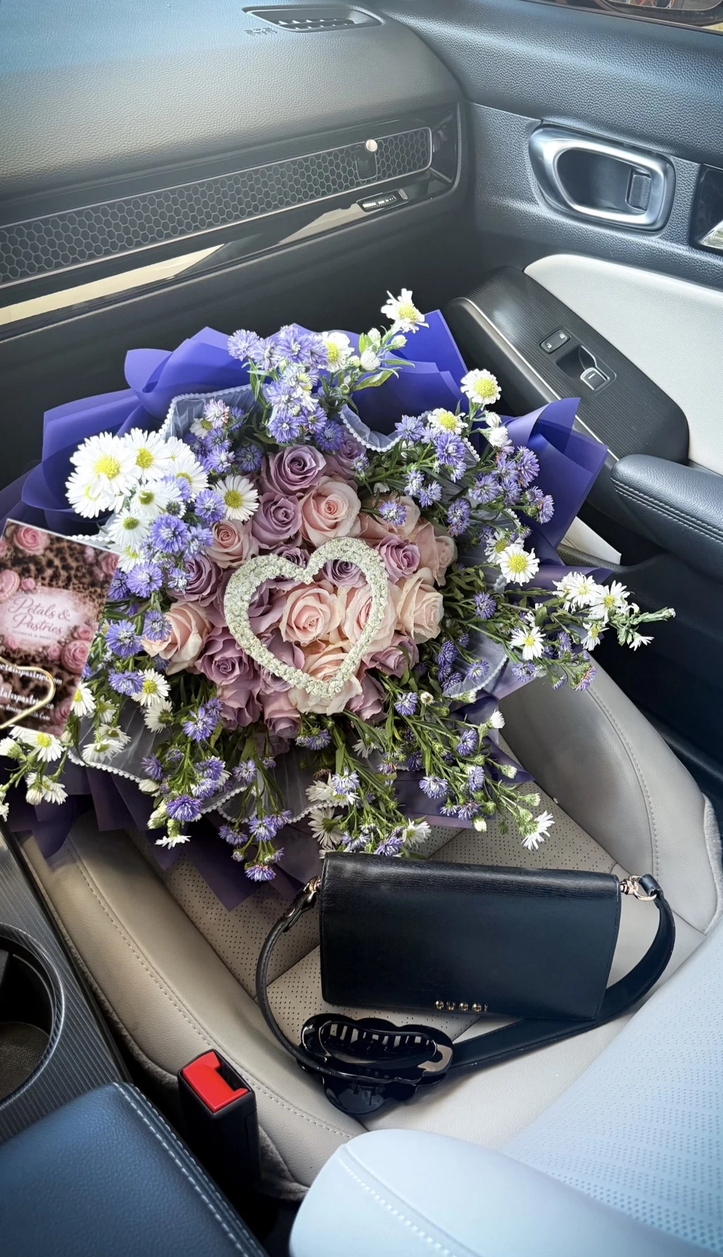 Purple and white bouquet with roses, daisies and baby’s breath in purple wrapping
