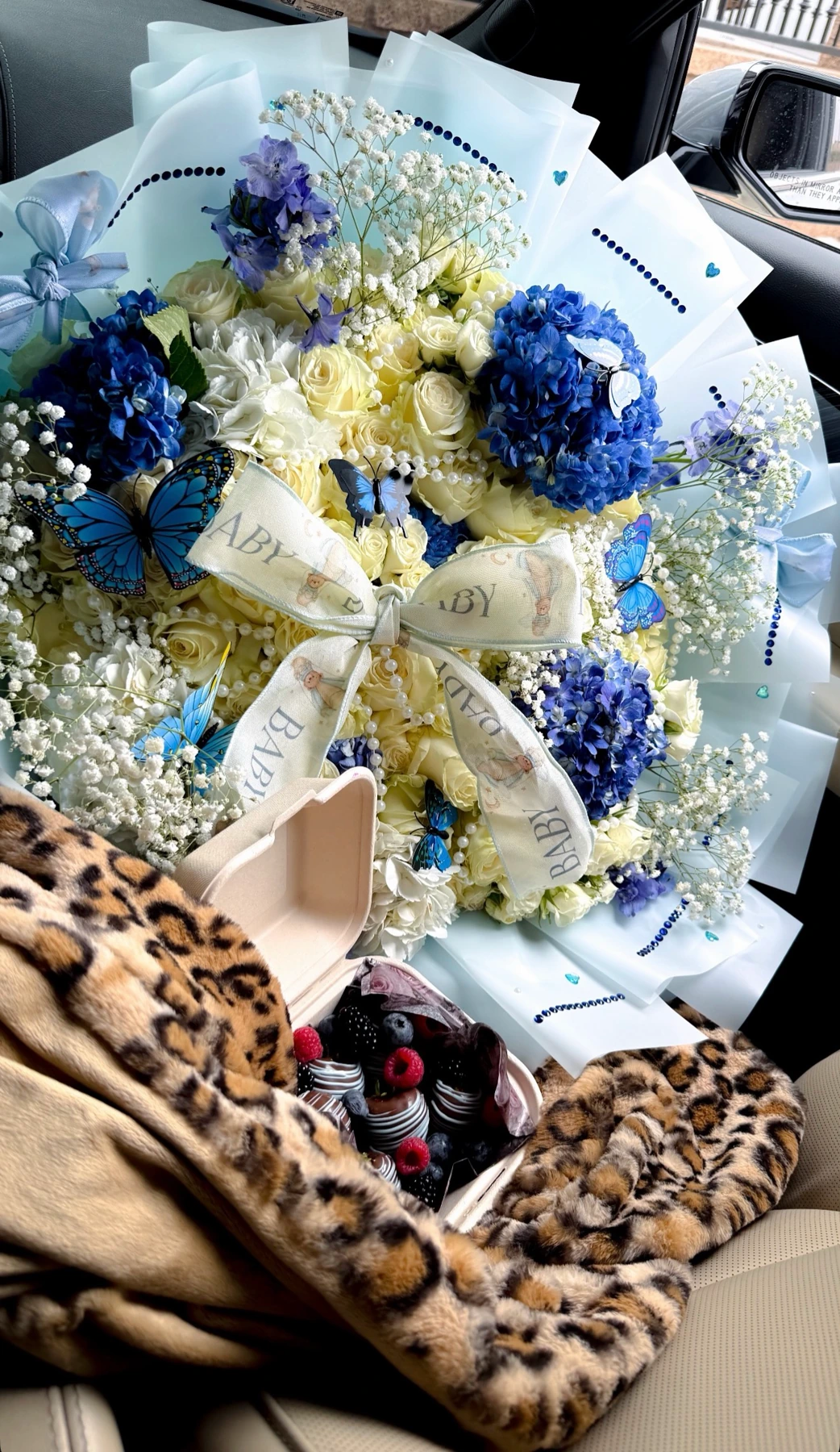 Cream roses, blue hydrangeas, baby’s breath and blue butterflies in pale blue wrapping
