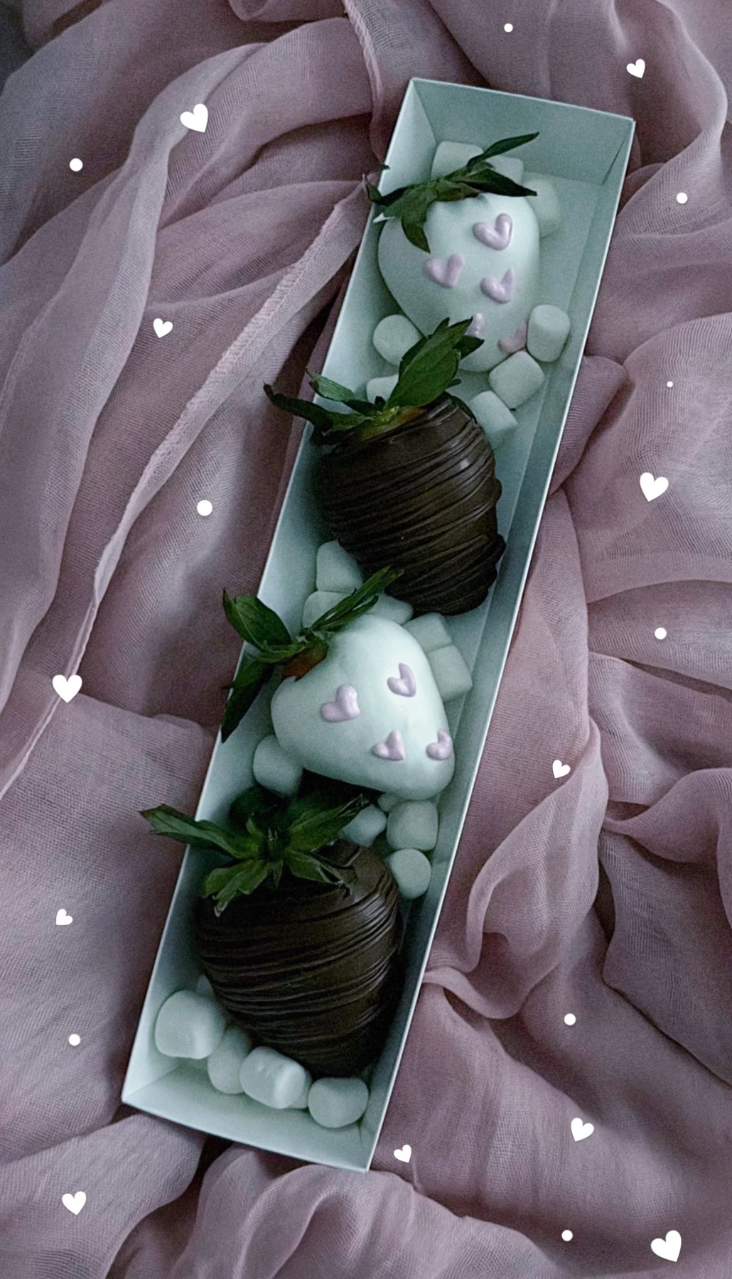 White and dark chocolate covered strawberries with lavender hearts on pink fabric