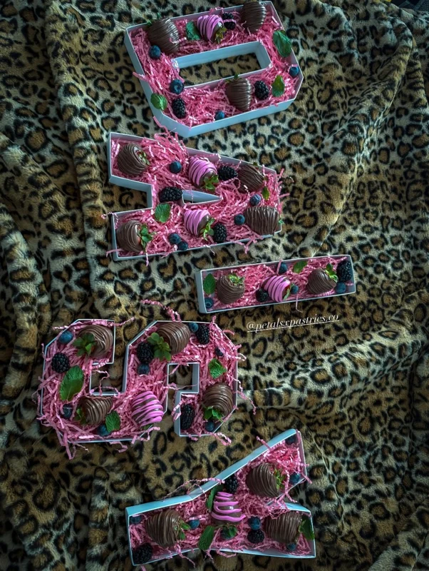 Personalized letter boxes of pink and chocolate dipped strawberries on animal-print fabric