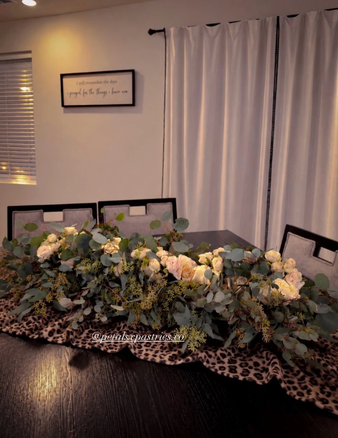 White roses and greenery arranged for a sweetheart wedding table