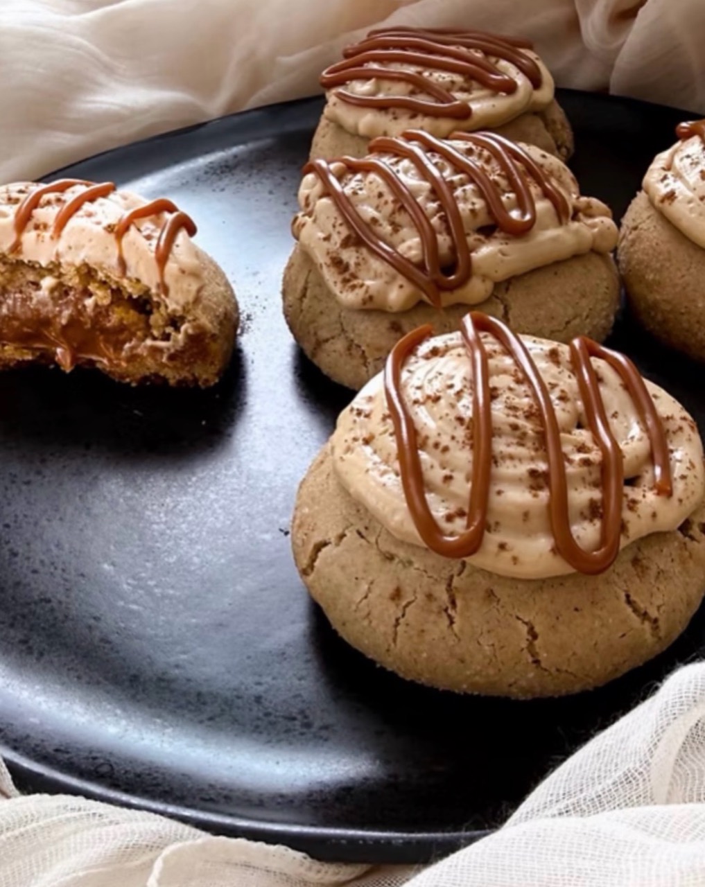 Frosted cookies with caramel-colored drizzle on a black plate